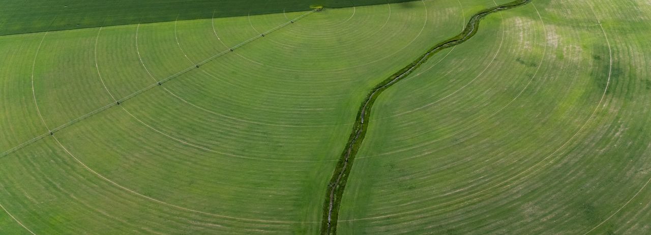 Vue aérienne de champs circulaires irrigués verts illustrant des techniques agricoles modernes.
